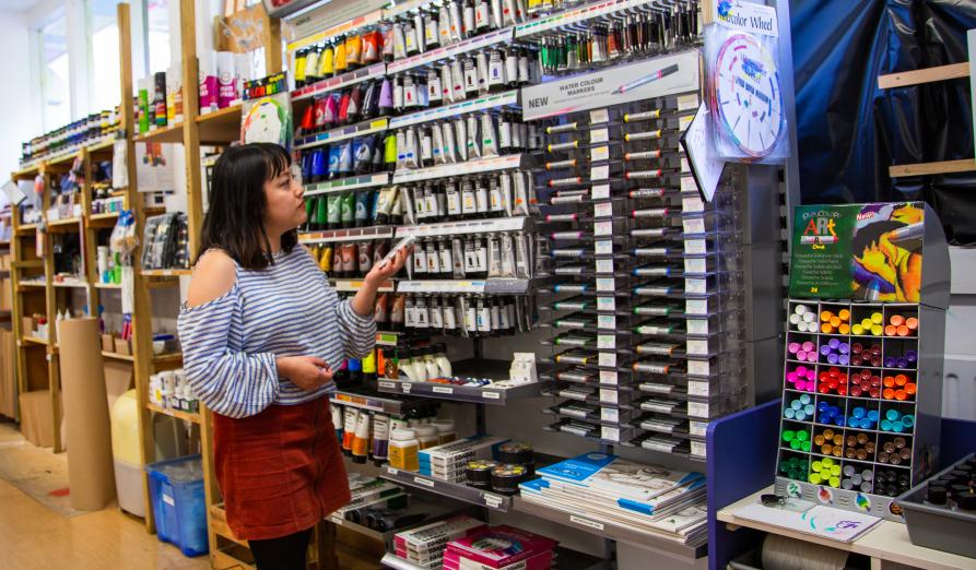 Woman in art supply shop browsing paint selection